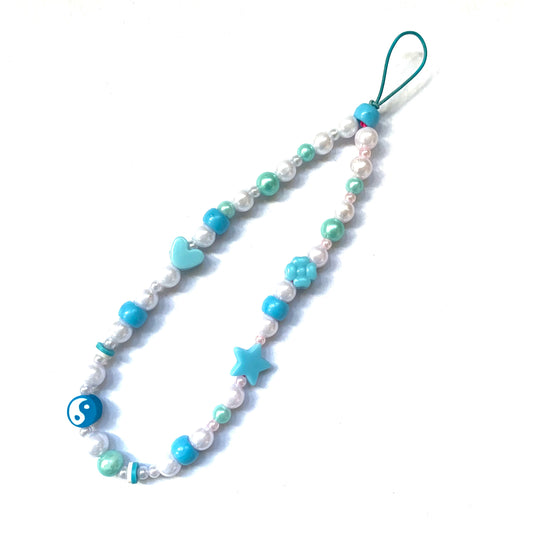 Blue phone charm featuring a blue yin and yang bead and matching faux white and blue pearls and other beads.