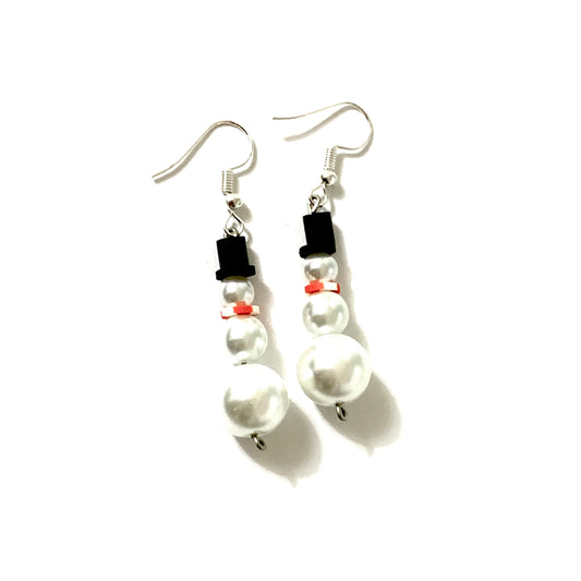 Silver fish hook snowman earrings. Featuring a snowman's body made of three pearls, a heishi bead for the scarf, and a black top hat.