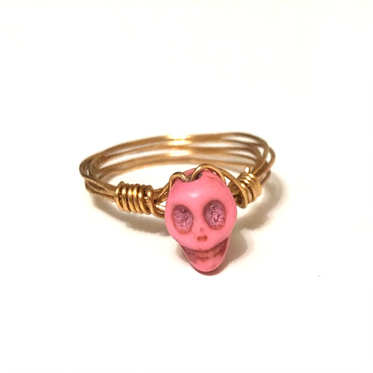 Close-up of gold wire ring with a small pink skull bead.