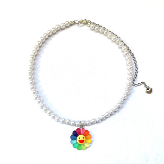 White faux pearl necklace with a large rainbow smiling flower charm.