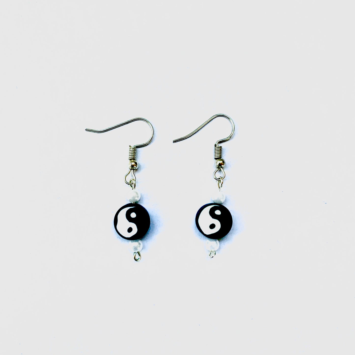 Pair of silver fish hook earrings with a black yin and yang polymer bead and two small faux pearls each.