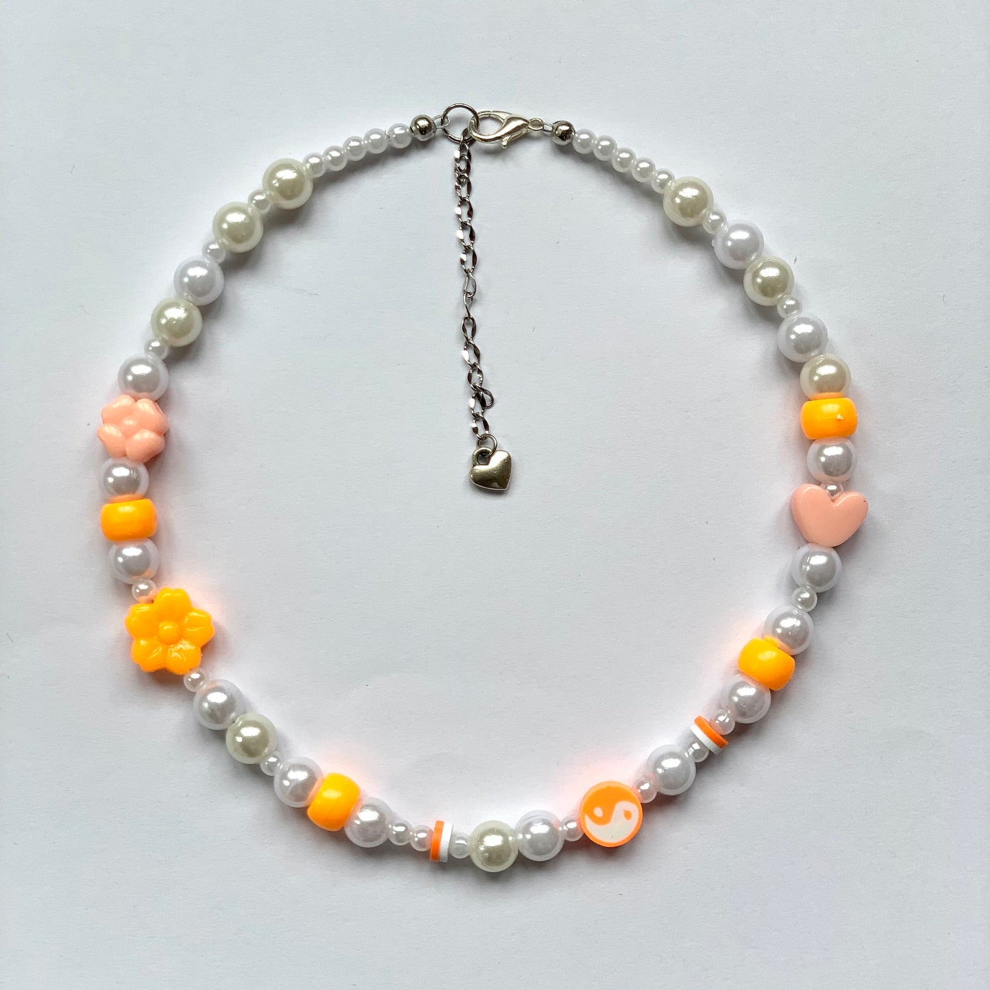 Beaded orange yin and yang necklace with faux white pearls.