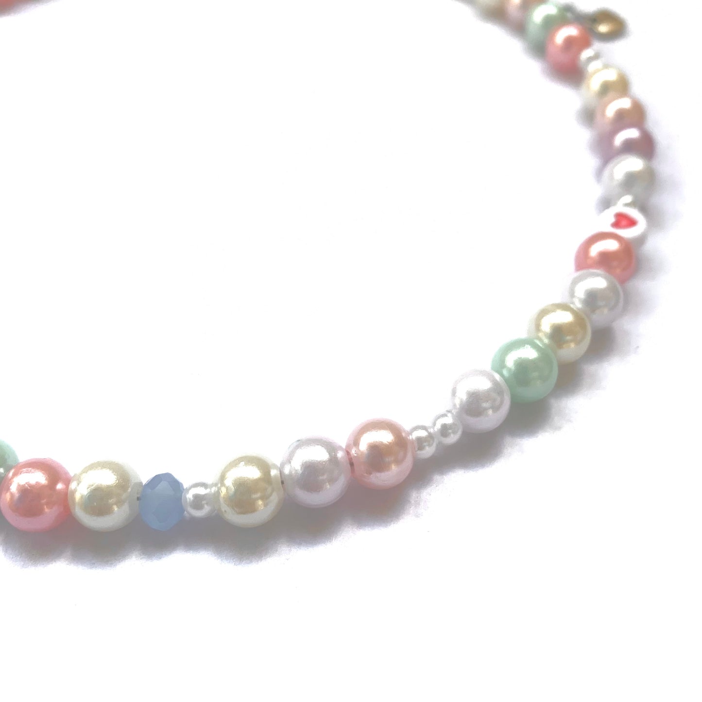 Close-up of a pastel necklace with beige, white, mint, pink, and purple pearls.